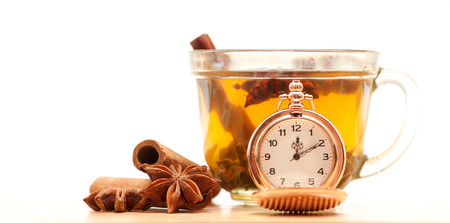 Cup of tea, spices and a pocket watch on a white background