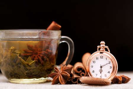 Cup of tea, spices and a pocket watch on a black backgroundの写真素材