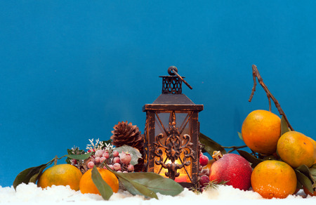 Beautiful Christmas decorations with candle lantern and tangerines on snowの写真素材