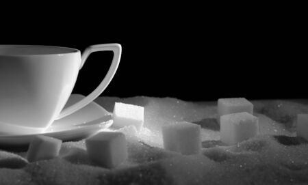 White tea cup and sugar on a black backgroundの写真素材
