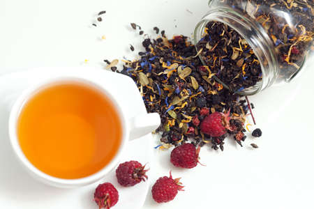 Tea and red ripe raspberry berries on white