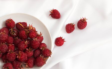 Red ripe raspberry berries in saucer on whiteの写真素材