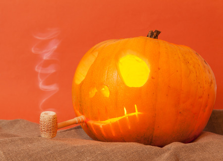 Beautiful Pumpkin on Halloween with a pipe on an orange backgroundの写真素材
