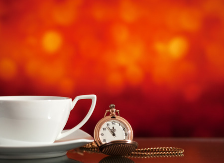 White tea cup and pocket watch on the bright blurred background with bokehの写真素材