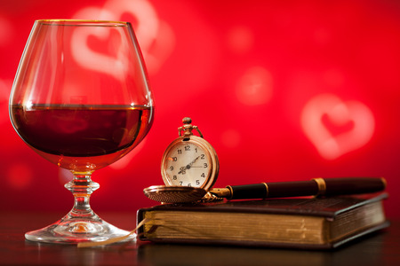 Brandy glass, diary and pocket watch on the bright blurred background with bokehの写真素材