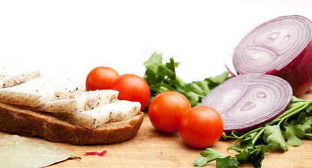 Lard on bread, tomatoes, onions fresh and herbs on a white backgroundの写真素材