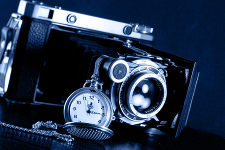Old retro camera and pocket watch on black background. Vintage camera closeup.の写真素材