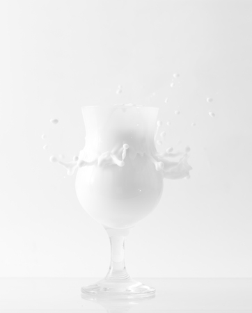 Beautiful glass with milk splash on a white backgroundの写真素材