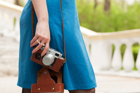 Woman on a blurred background holds an old retro cameraの写真素材