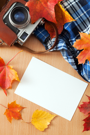 Retro camera and photos on the table with autumn leavesの写真素材