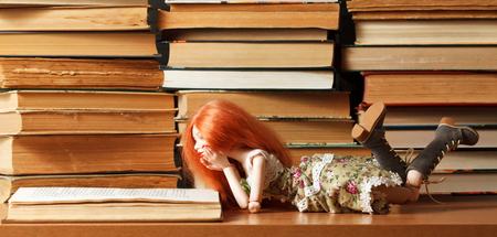 Beautiful red-haired bjd doll and a bookの写真素材
