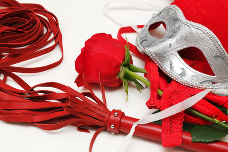 Red whip, rose and mask on a whiteの写真素材
