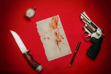 Revolver, hunting knife and a sheet of paper in blood on the tableの写真素材