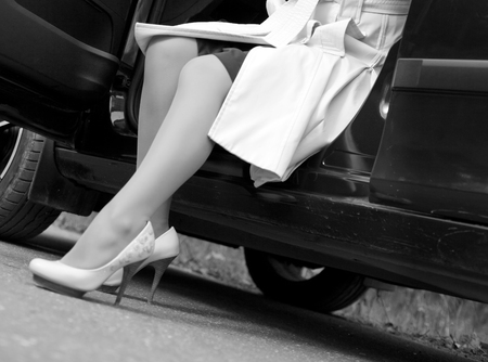 Women's legs in white shoes from the car. Woman in white shoes gets out of the carの写真素材