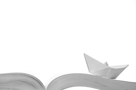 Paper boat on the opened book on a white backgroundの写真素材