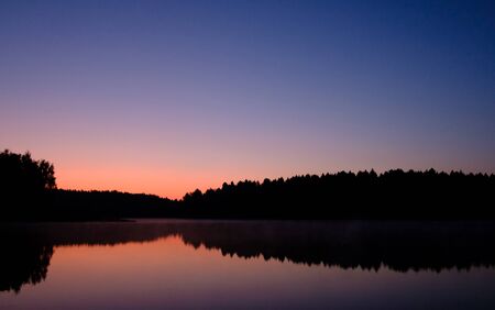 early morning sunrise over a lake on a forest backgroundの写真素材