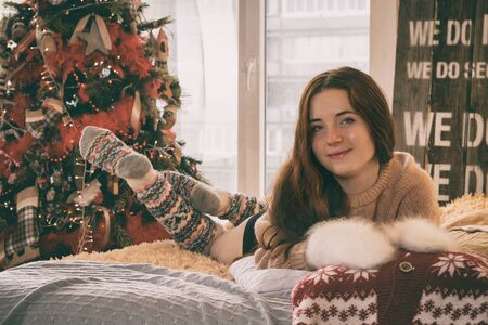 beautiful young woman lies on the bed near the new year treeの写真素材