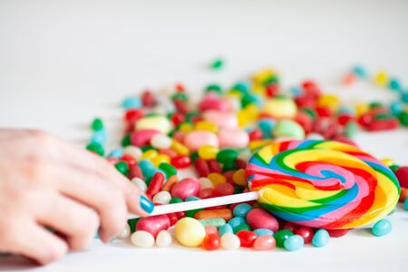 colored candy lollipops and a female hand on a white backgroundの写真素材