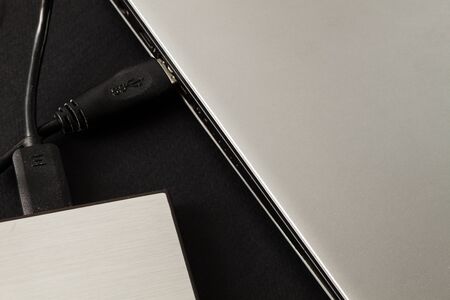 laptop connected to an external hard drive on a black background