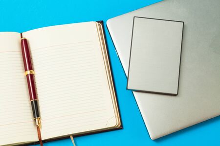 open diary with pen and laptop on a blue background