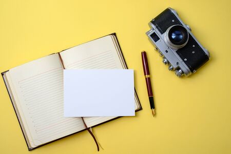 beautiful old vintage retro camera, diary with pen and photo card on a yellow backgroundの素材 [FY310142181350]