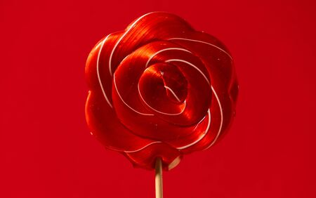 beautiful red candy caramel on a stick on a red backgroundの写真素材