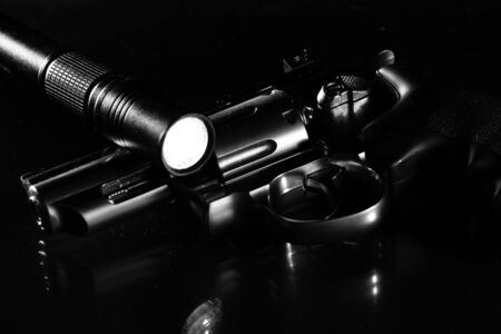 revolver and flashlight on a black background