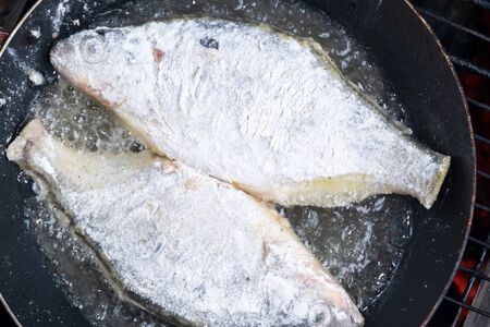 beautiful freshly caught fish is fried in a pan in oilの写真素材