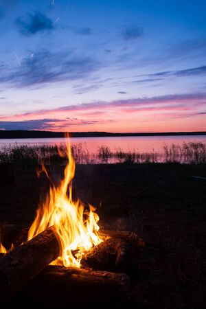 evening bonfire on the lake and beautiful sunset in the skyの写真素材