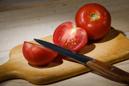 red tomato and knife on a cutting boardの写真素材