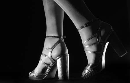 Female feet in high heeled sandals on blackの写真素材