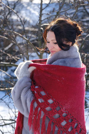 beautiful adult woman in a fur coat and with a shawl in nature in winterの写真素材