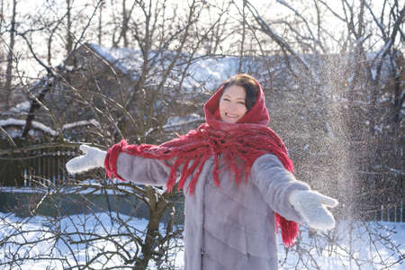 beautiful adult woman in a fur coat and scarf outdoors in winterの写真素材