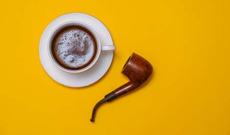 cup with coffee and smoking pipe on a yellow background