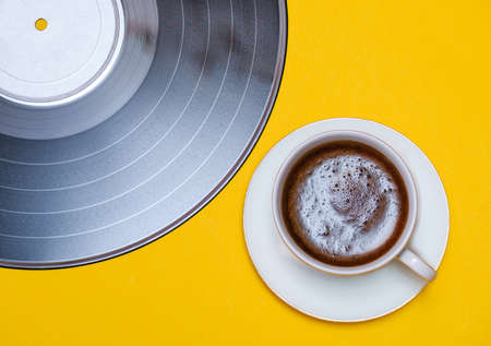 old vinyl record and coffee cup on yellow background