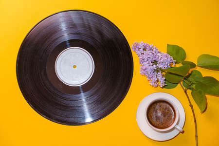 old vinyl record, cup of coffee and blossoming branch of lilac on yellow backgroundの写真素材