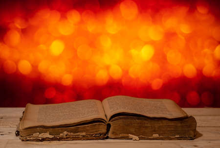 an old open book lies on a wooden table against a background of beautiful bokehの写真素材
