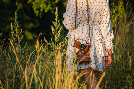 woman in a summer short dress with an old camera on her shoulder