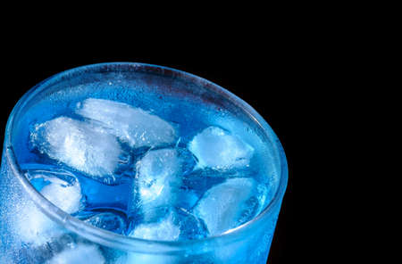 glass with ice and blue cocktail on black backgroundの写真素材