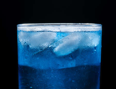 glass with ice and blue cocktail on black backgroundの写真素材