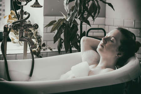beautiful woman lies in a bath with foam