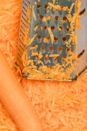 grated carrots and metal grater top close upの写真素材