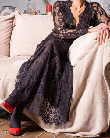 a slender woman in a transparent black dress sits on a sofaの写真素材