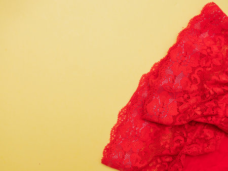 beautiful red stockings with openwork elastic band lie on yellow background close-upの写真素材