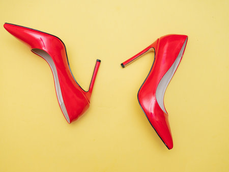 red patent leather shiny women's stiletto heels lie on yellow backgroundの写真素材