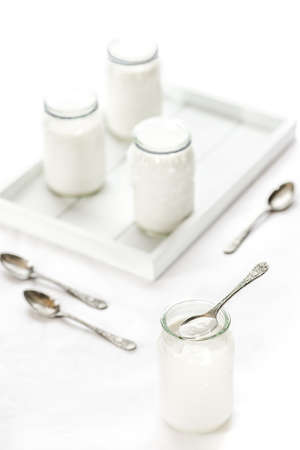 Four pots of homemade yogurt on white background