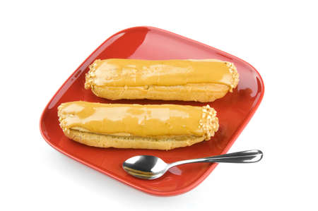 Two eclaires on a red plate with a spoon