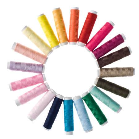 Circle of coloured bobbins of thread on white background
