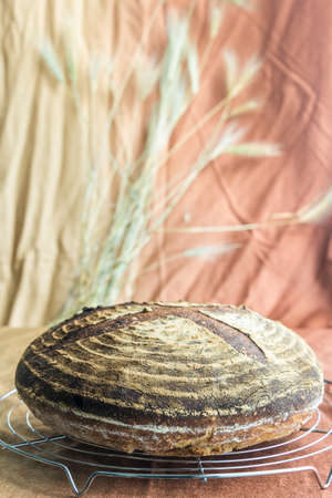Simple sourdough bread on a warm background with ears of wheat