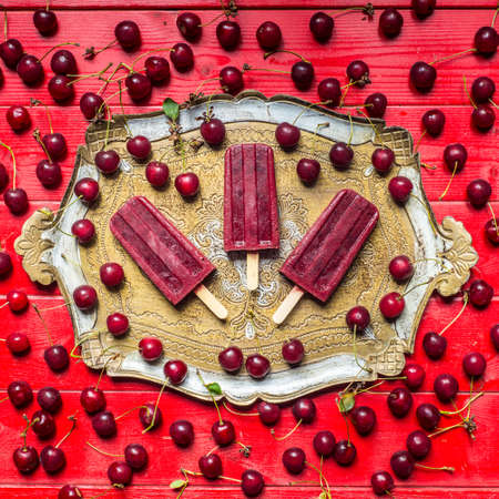 Homemade sour cherry popsicles on a vintage plateの写真素材